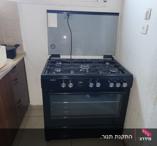 תנור גז שחור עם כפתורים וכיריים עליונים